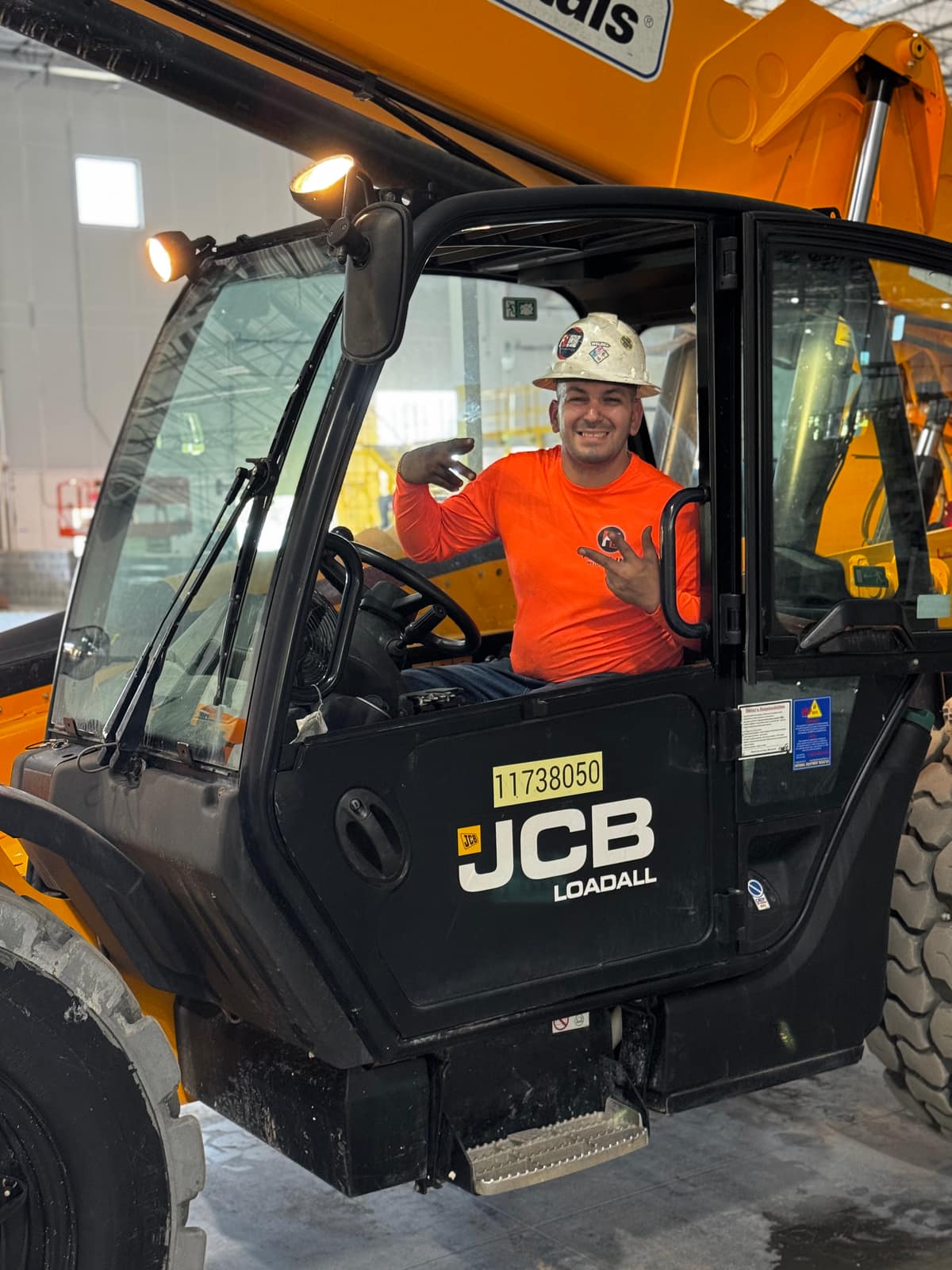 Fine Line Weld & Build team member in a hard hat at the controls of a JCB telehandler