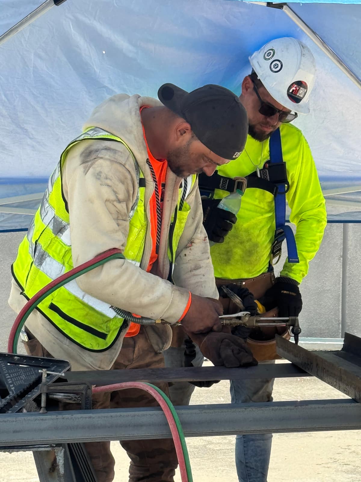 Two workers in hi-vis using an oxy-fuel torch on structural steel on site