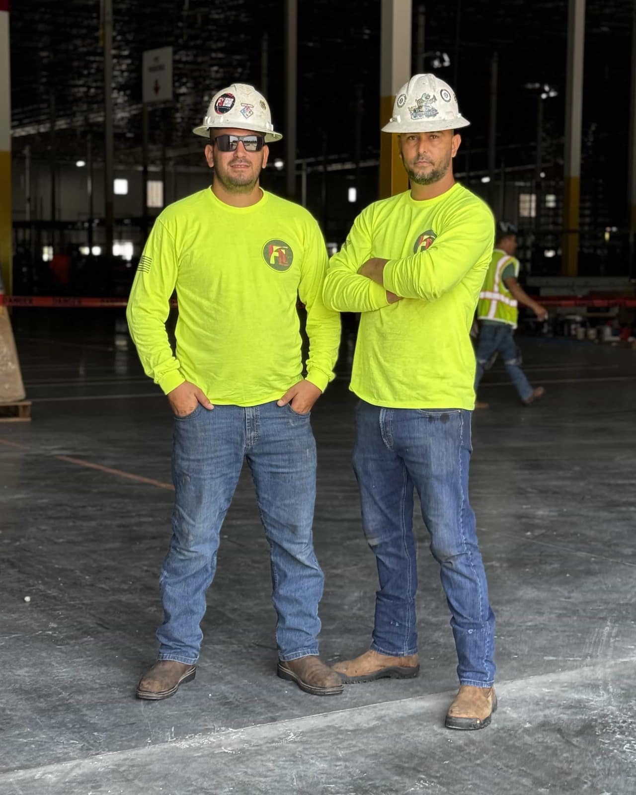 Ismael Torres and Guelmi Jimenez, the owners of Fine Line Weld & Build, in hard hats and branded hi-vis shirts inside a warehouse under construction