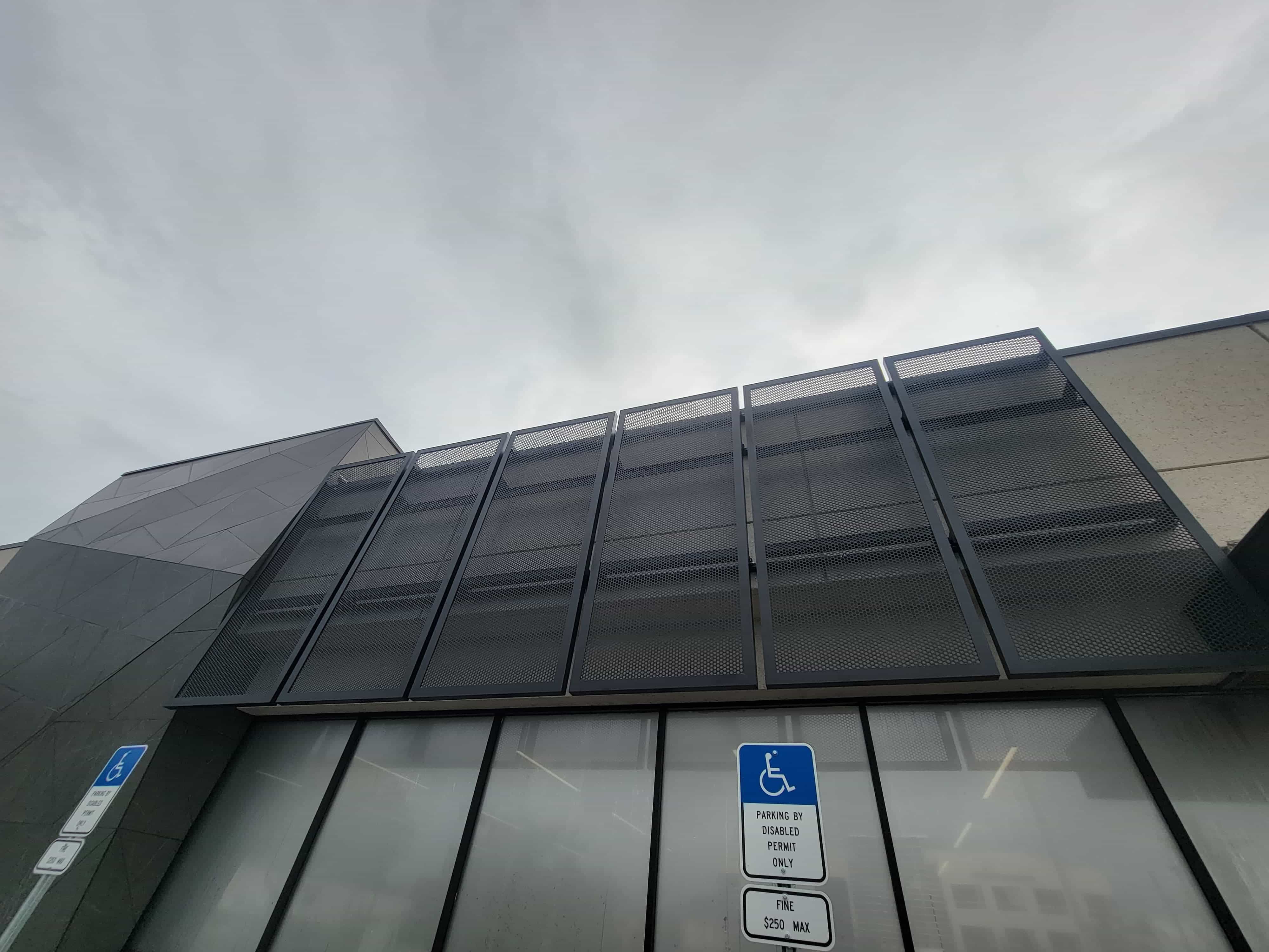 Perforated metal screen panels on a steel frame above a commercial building entrance