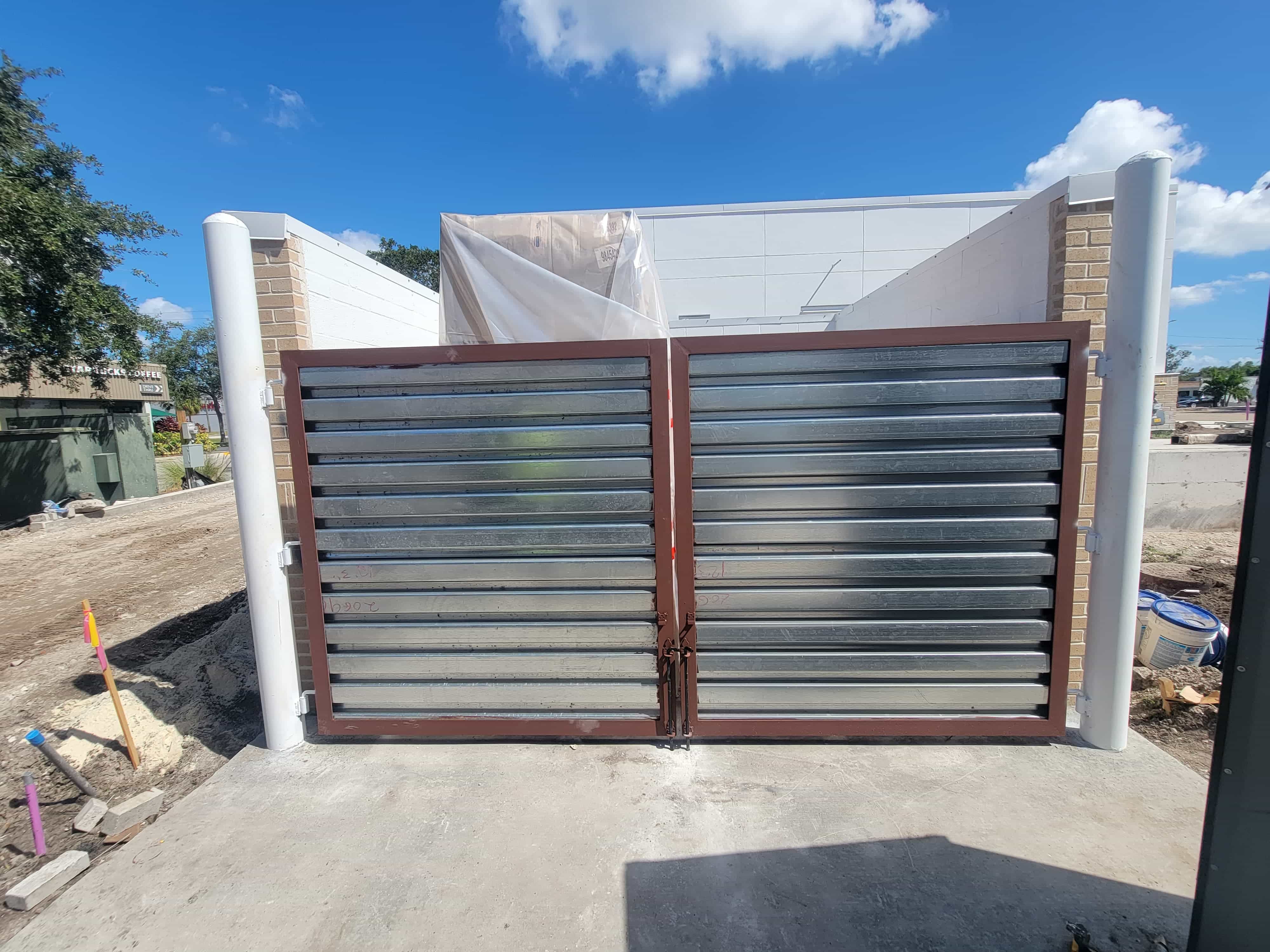 Galvanised louvre enclosure gates in a welded steel frame between masonry posts
