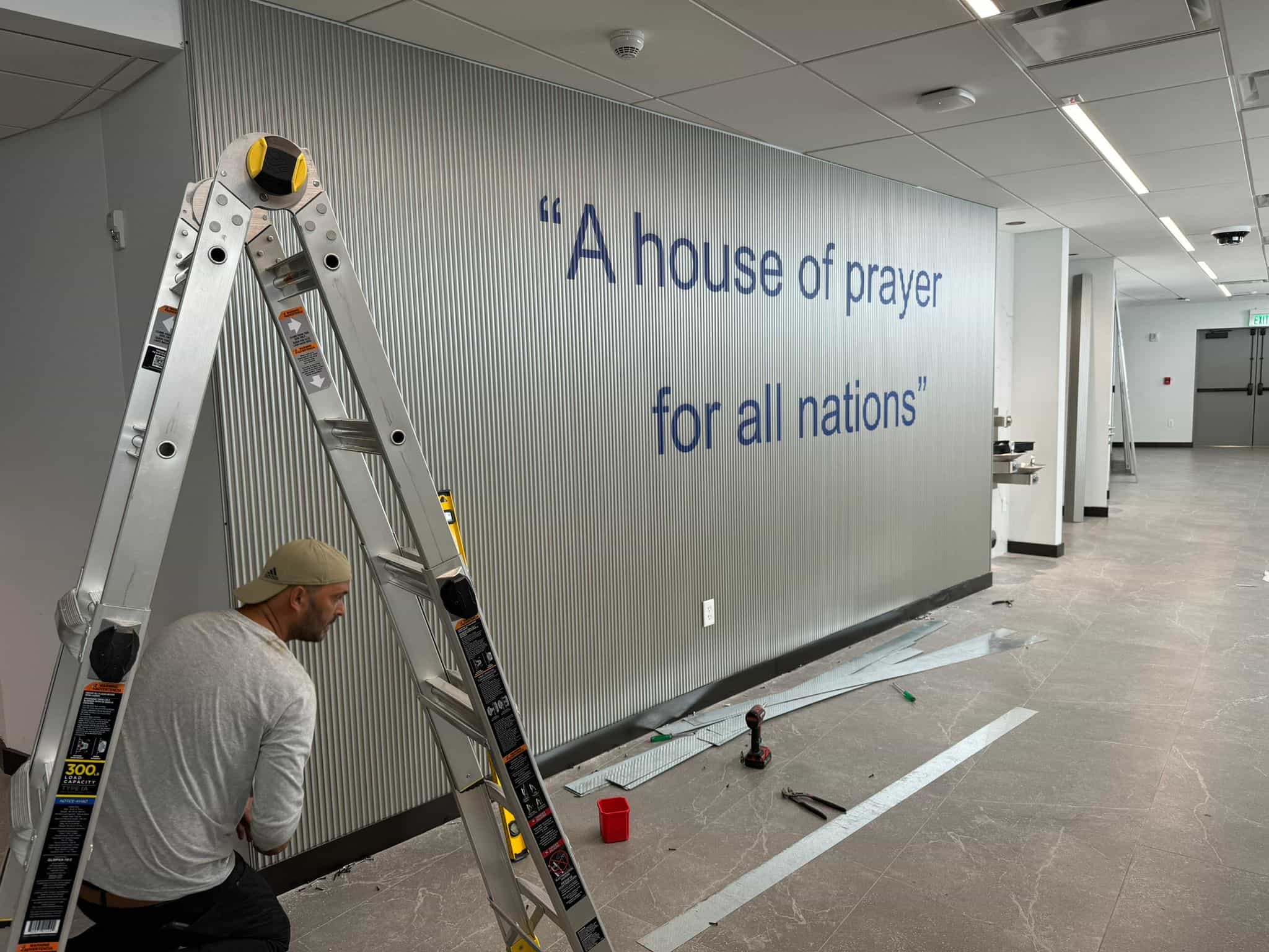 Installer fitting corrugated metal wall panels inside a commercial interior