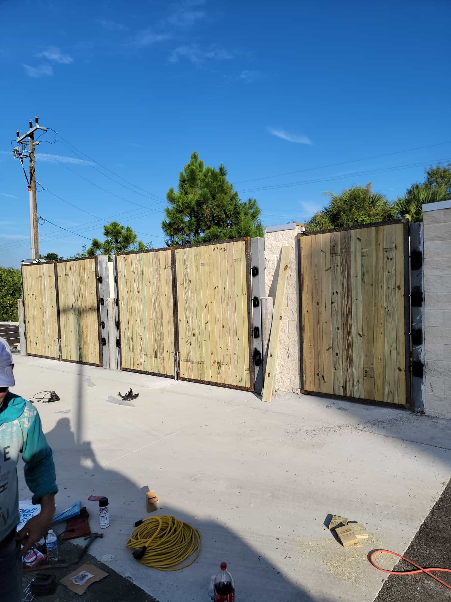 Steel-framed gates with timber infill hung on masonry posts at a service enclosure